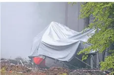  ?? FOTO: PIERO CRUCIATTI/DPA ?? Ein Tag nach dem Unglück: Die abgestürzt­e Gondel liegt mit einer Plane verdeckt neben einem in Nebel bedeckten Waldstück.