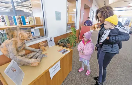  ?? PHOTOS BY LUIS SÁNCHEZ SATURNO/THE NEW MEXICAN ?? Lydia Ausberry of Santa Fe talks to her children, Angelina Ausberry, 5, and Carlo Ausberry, 7 months, about a new sculpture by artist Hernan Gomez Chavez called Huehueteot­l ,or Old God, on Tuesday at the Southside Branch Library.