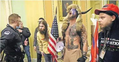  ??  ?? Jacob Chansley (in horns) and other protesters interact with Capitol Police Jan. 6 inside the U.S. Capitol Building in Washington. [WIN MCNAMEE/GETTY IMAGES VIA TRIBUNE NEWS SERVICE]