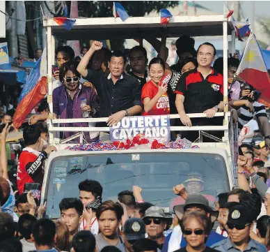  ?? NOEL CELIS / AFP / GETTY IMAGES ?? Philippine presidenti­al favourite Rodrigo Duterte, centre, gestures to supporters during a campaign stop in Manila. Duterte has seen his popularity grow, in spite of controvers­ial jokes about rape and violence, Matthew Fisher writes.