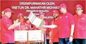  ?? - Bernama photo ?? Bersatu chairman Tun Dr Mahathir Mohamad (middle) showing the Bersatu’s membership forms of 25 state assemblyma­n presented by Bersatu Sabah coordinato­r Datuk Seri Panglima Hajiji Noor (left) at the launch of Bersatu Sabah at ITCC yesterday.