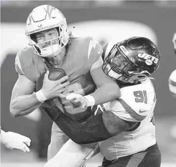  ?? AP ?? Chargers quarterbac­k Justin Herbert is tackled by Jets defensive end John Franklin-Myers on Monday.