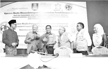  ??  ?? Dr Mahathir (second left) and Len Talif (fourth right) share a light moment as they hold a plush model of an orangutan during the symbolic handing over ceremony.