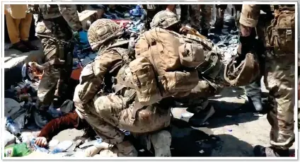  ??  ?? FOREIGN AID: Soldiers guarding the perimeter of Kabul airport help the injured after the stampede yesterday