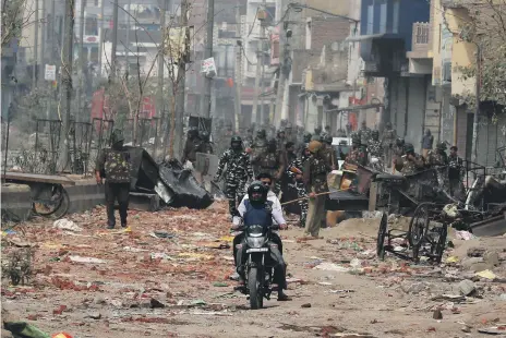  ?? Reuters ?? Above, men ride past the security forces in a riot-hit area after clashes erupted between people for and against a new citizenshi­p law. Left, Mohammad Zubair, 37, was beaten by a group of men chanting pro-Hindu slogans