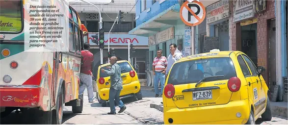  ??  ?? Dos taxis están parqueados en el andén de la carrera 38 con 45, zona donde se prohíbe parquear, mientras un bus frena con el semáforo en verde para recoger un pasajero.