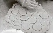  ??  ?? Donin cuts circles out of dough while demonstrat­ing how to make traditiona­l hamantasch­en.
