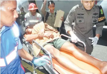  ??  ?? Indonesian police officers and airport officials push a stretcher with a survivor after they arrived in Timika, Papua province.