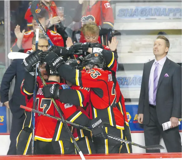  ?? — JIM WELLS/POSTMEDIA NEWS ?? The Calgary Flames and head coach Glen Gulutzan celebrate clinching a playoff berth after defeating the San Jose Sharks at the Saddledome on Friday night. The Flames have played to a 20-6-1 mark over their last 27 games.