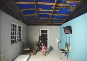  ?? AP Photo/Carlos Giusti ?? Housing: Above, In this Dec. 21, 2017, file photo, two year old Yeinelis Oliveras González accompanie­s her father, Luis Oliveras, while eating dinner, in Morovis, Puerto Rico. The light blue glow cast by a tarp that covers half their roof, a donation...