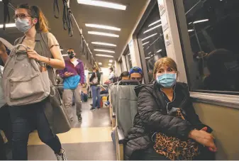  ?? Mike Kai Chen / Special to The Chronicle ?? Masked passengers ride BART through S.F. Face coverings are a symbol of the pandemic.