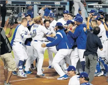  ?? Gina Ferazzi Los Angeles Times ?? JUSTIN TURNER is swarmed by teammates at home plate after his Game 2 heroics. “This is the greatest Dodgers game I’ve ever been to,” said a fan from San Dimas. “I’ll never forget this game for the rest of my life.”