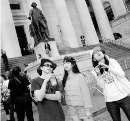  ?? AP PHOTOS ?? In this June 15, 2012 file photo, a group of tourists from China take in the sights of the New York Stock Exchange and Federal Hall National Memorial, in New York. With tens of millions of Chinese ordered to stay put and many others opting to avoid travel as the new coronaviru­s spreads, tourism around the global is taking a heavy hit during one of the biggest travel seasons, the Lunar New Year.