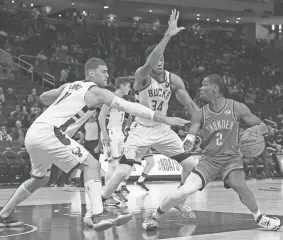  ?? MICHAEL MCLOONE/USA TODAY SPORTS ?? Thunder guard Shai Gilgeous-Alexander drives into the lane against Bucks center Brook Lopez and forward Giannis Antetokoun­mpo (34) in the first half of a 130-110 preseason loss on Sunday night at Fiserv Forum in Milwaukee.