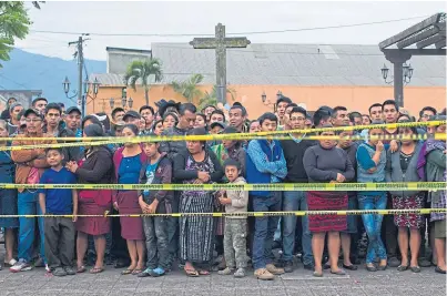  ?? Pictures: AP. ?? Neighbours stand outside a temporary morgue near Volcan de Fuego.