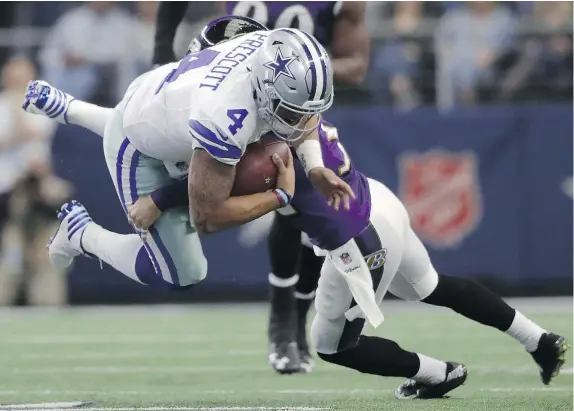  ?? — GETTY IMAGES ?? Dallas Cowboys quarterbac­k Dak Prescott, left, is tackled by Eric Weddle of the Baltimore Ravens during the second quarter of a game at AT&T Stadium in Arlington, Texas on Sunday. Prescott passed for more than 300 yards for the second straight week.