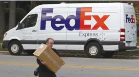  ??  ?? A FEDEX delivery worker carries a package for a delivery in Wilmette, Illinois, Oct. 27, 2015.