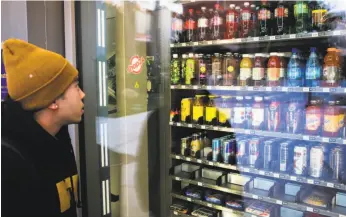  ?? Gabrielle Lurie / Special to The Chronicle ?? Zack Armada decides which drink to buy from one of the outdoor vending machines at San Francisco State on Thursday.