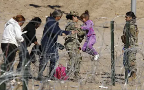  ?? HERIKA MARTINEZ/AGENCE FRANCE-PRESSE ?? TEXAS National Guard agent carries a migrant girl over a barbed fence on the banks of the Rio Grande in El Paso, state of Texas, United States, border with Ciudad Juarez, state of Chihuahua, Mexico.