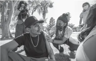  ?? Tribune News Service/los Angeles Times ?? Asia Hartford, LVN, right, gives Luis Fernandez, 28, a vaccine in Ted Watkins Memorial Park on May 5 in Los Angeles.