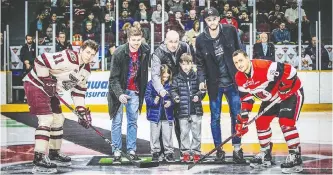 ??  ?? Five days after winning the national title, Dave Smart, middle, accompanie­d by his sons Gabe, middle left, and Theo, middle right, as well as Carleton Ravens men’s basketball team members Mitch Wood, second left, and Mitch Jackson, second right, drops a ceremonial puck at an Ottawa 67’s game against the Peterborou­gh Petes.