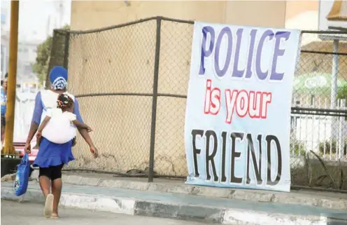  ??  ?? A woman walks by a “Police is your Friend” banner at Mobolaji Bank-Anthony Way in Ikeja, Lagos