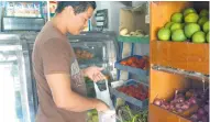  ??  ?? El tendero Carlos Jiménez, en Los Nogales, recoge en una bolsa las verduras de su próxima venta.