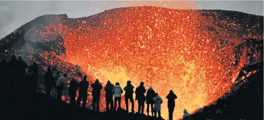 ?? Picture: iStock ?? SONGS OF FIRE AND ICELAND Adventurer­s watch the eruption of Eyjafjalla­jokull, just metres from the molten lava.