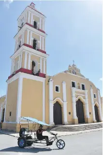  ??  ?? A bicycle taxi passes by the beautiful San Juan Bautista Roman Catholic Church in the colonial town of Remedios in central Cuba.