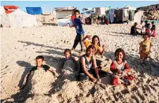  ?? ?? Palestinia­n children pose for a picture on a beach in Deir el-Balah in the central Gaza Strip.