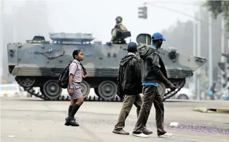  ?? Zimbabwští vojáci včera blokovali v centru metropole Harare přístup k vládním úřadům, k parlamentu a k soudním budovám. FOTO ČTK/ AP ?? Transporté­ry v ulicích.