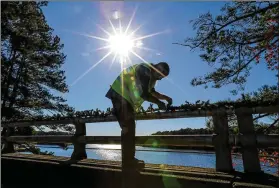  ?? JOHN SPINK/ JOHN. SPINK@ AJC. COM ?? Stone Mountain Park worker James Mcghee and others decorated the bridges spanning over Stone Mountain Lake with Christmas garland Nov. 13, getting ready for the park’s Stone Mountain Christmas that runs through Jan. 3. With Thanksgivi­ng plans curtailed or canceled, many folks say they are needing something merry and bright to raise their spirits.