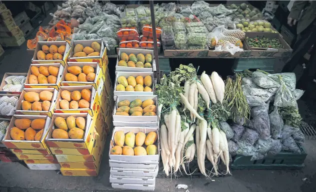  ?? AFP ?? Fruit and vegetables are displayed for sale at a food stall at Whitechape­l Market in east London. Accelerati­ng inflation coupled with muted wage growth puts the squeeze on households.