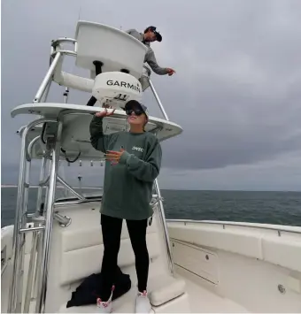  ?? NANCY LANE / HERALD STAFF FILE ?? THERE! Matt Mendoza, captain of Afishinsea, an Atlantic White Shark Conservanc­y charter boat, points out sharks off Monomoy Island as naturalist Maddie Poirier, with the Atlantic White Shark Conservanc­y, looks out for more on Sunday in Chatham.