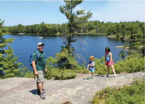  ?? JENNIFER BAIN PHOTOS/TORONTO STAR ?? In June, just before school ends, Parks Canada’s Ethan Meleg shows Charlie and Hazel MacKenzie the scenery at picturesqu­e Fairy Lake.