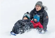  ?? ERROL MCGIHON ?? Nick Wang enjoys a toboggan run with his children Renny, 8, and Robin, 21/2, at Walter Baker Park in Kanata.