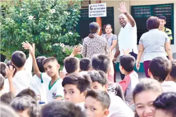  ?? (SUN.STAR FOTO/ALLAN CUIZON) ?? NEW SCHOOL. GMR-Megawide Cebu Airport Corp. chief executive adviser Andrew AcquaahHar­rison waves to the students of the Ibo Elementary School, where the airport management intends to build a new school building within the year.