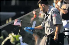  ??  ?? A worker polishes the bronze parapets at the 9/11 Memorial where the names of the 2,983 victims of the attacks on 11 September 2001 and 26 February 1993 are inscribed, on 8 September 2021 in New York City, 20 years after al-Qaeda terrorists flew two planes into the towers at the World Trade Center. Photo: Chip Somodevill­a/Getty Images