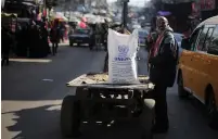  ?? (Ibraheem Abu Mustafa/Reuters) ?? A MAN STANDS next to a cart carrying a sack of flour distribute­d by UNRWA, in Gaza’s Khan Yunis refugee camp, last week.