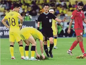  ?? PIC BY AIZUDDIN SAAD ?? A Malaysia player reposition­s the grass on the pitch during Tuesday’s World Cup qualifier against Oman at the National Stadium in Bukit Jalil.