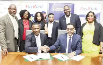 ?? ?? Cecil Foster (sitting at left), Chief Executive Officer of FosRich Company Ltd shakes hands with Brandon Hayden, Managing Director of JN Fund Managers Ltd following a signing agreement to formalise the successful execution of J$900 million bond raise for FosRich Company Ltd. (JN Group photo)