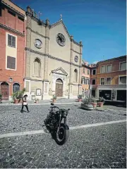  ?? /AFP ?? No business: A woman wearing a face mask walks past a motorbike parked near St Biagio church in an empty central Tivoli, during the Covid-19 lockdown, which is putting tourist towns across Italy at risk.