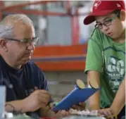  ??  ?? Stem Minds program director Reza Beyzaei helps Arteen Mirzai, 12 put together his own electric car. Organizers hope the event encourages children to take an interest in how their beloved electronic­s are made — perhaps even spark an interest in a future...