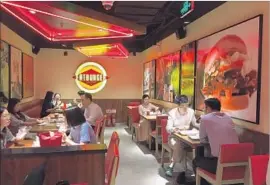  ?? Jessica Meyers For The Times ?? CHINESE DINERS eat at a Fatburger location in a Beijing bank. The chain’s presence here ref lects not just its global ambitions, but changing Chinese tastes.