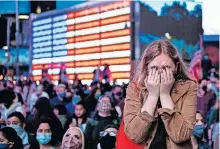  ?? THE ASSOCIATED PRESS] ?? Fletcher Peters of New York, a journalism student at NYU, reacts as she watches President-elect Joe Biden on a monitor in Times Square on Saturday in New York, as he addressed the nation. [CRAIG RUTTLE/