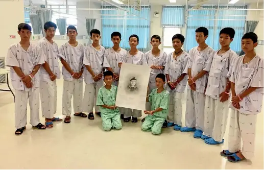  ?? AP ?? The rescued soccer team members posing with a sketch of the Thai Navy SEAL diver who died while trying to rescue them.