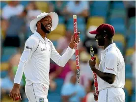  ?? GETTY IMAGES ?? West Indies allrounder Roston Chase, left, who took eight for 60, celebrates the first-test win over England with Kemar Roach.