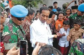  ??  ?? Indonesian President Joko Widodo (centre) and his running mate Ma’ruf Amin (center right) speak with residents in a neighbourh­ood in Jakarta, on Tuesday.