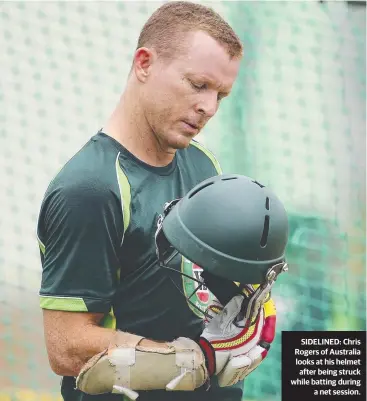  ??  ?? SIDELINED: Chris Rogers of Australia looks at his helmet
after being struck while batting during
a net session.