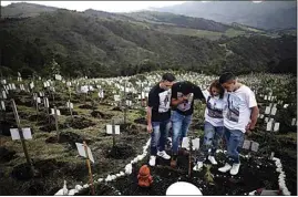  ?? IVAN VALENCIA / AP ?? Relatives of Luis Enrique Rodriguez, who died of COVID-19, visit where he was buried on a hill at the El Pajonal de Cogua Natural Reserve, in Cogua, Colombia last month.
